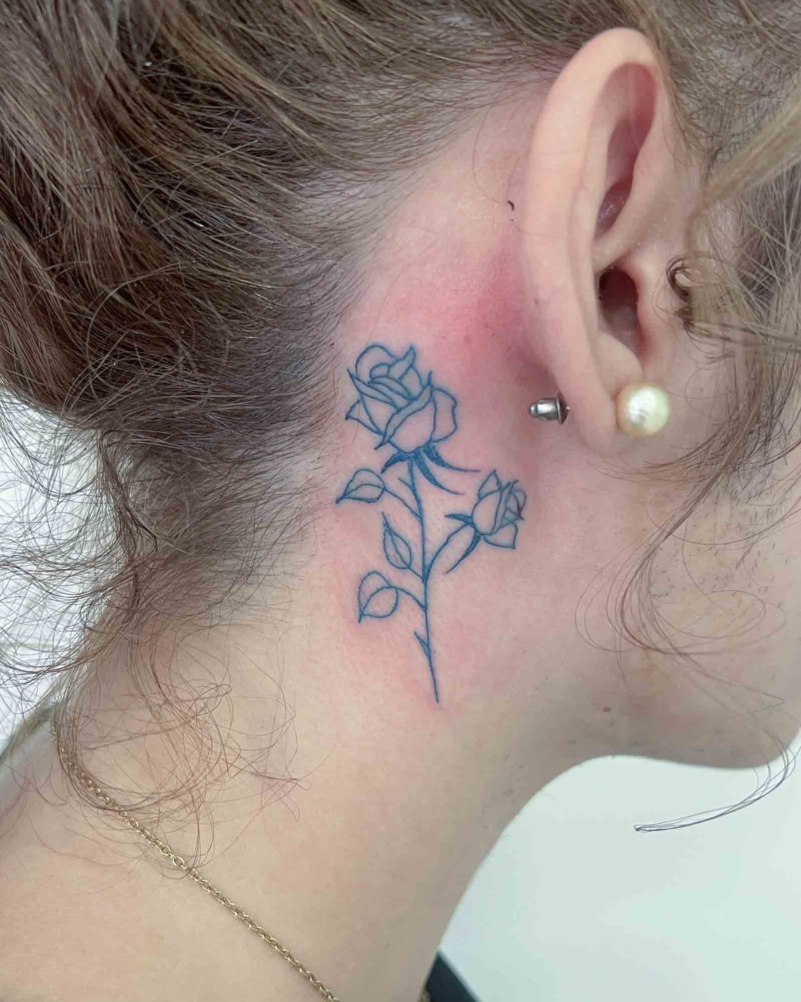 tatuaje rosa línea fina estilo minimal detrás de la oreja