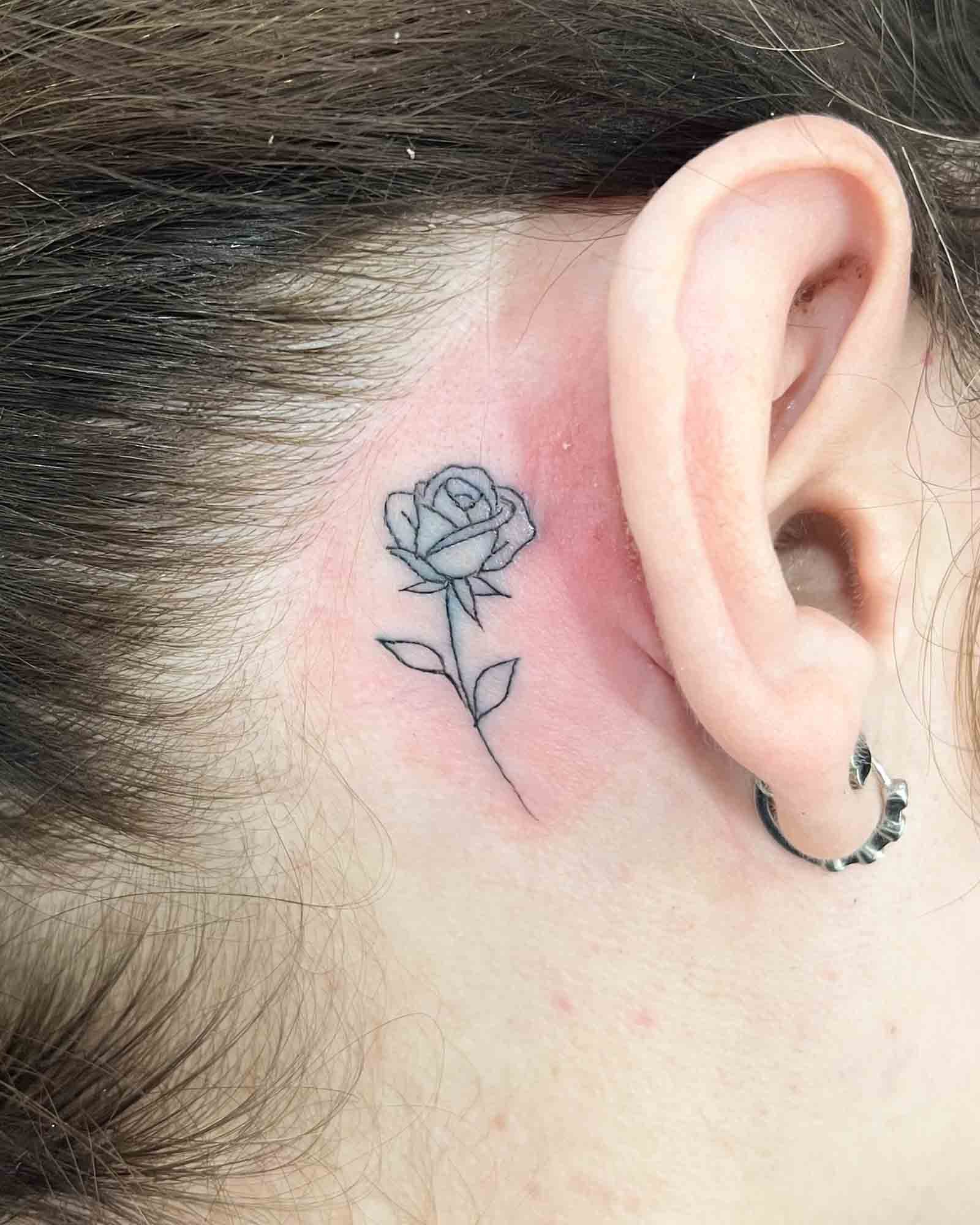 tatuaje rosa pequeña línea fina detrás de la oreja